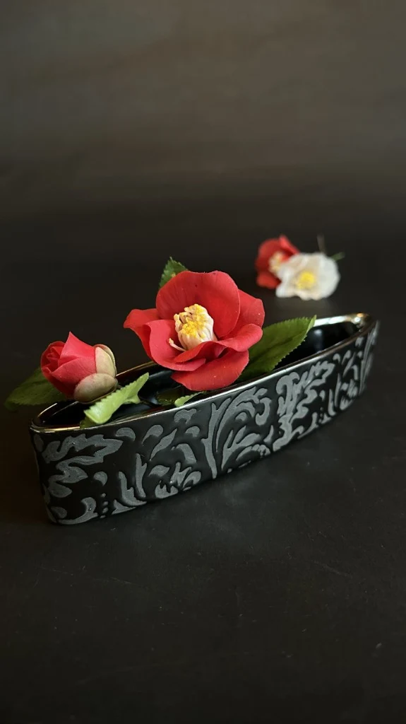 黒漆調の花器に生けたヤブツバキの一輪
